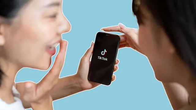 Two people looking at a phone displaying the TikTok logo