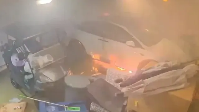 A car burning inside a garage in an archived news-video frame