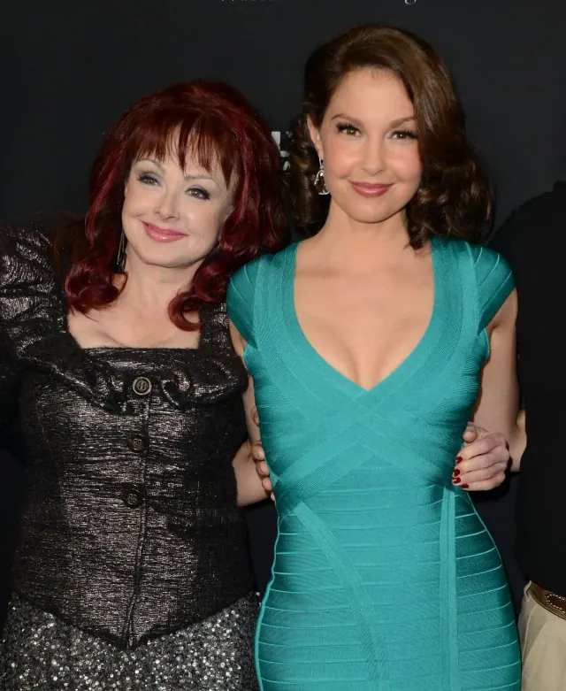 Naomi Judd in black standing beside Ashley Judd in a turquoise dress