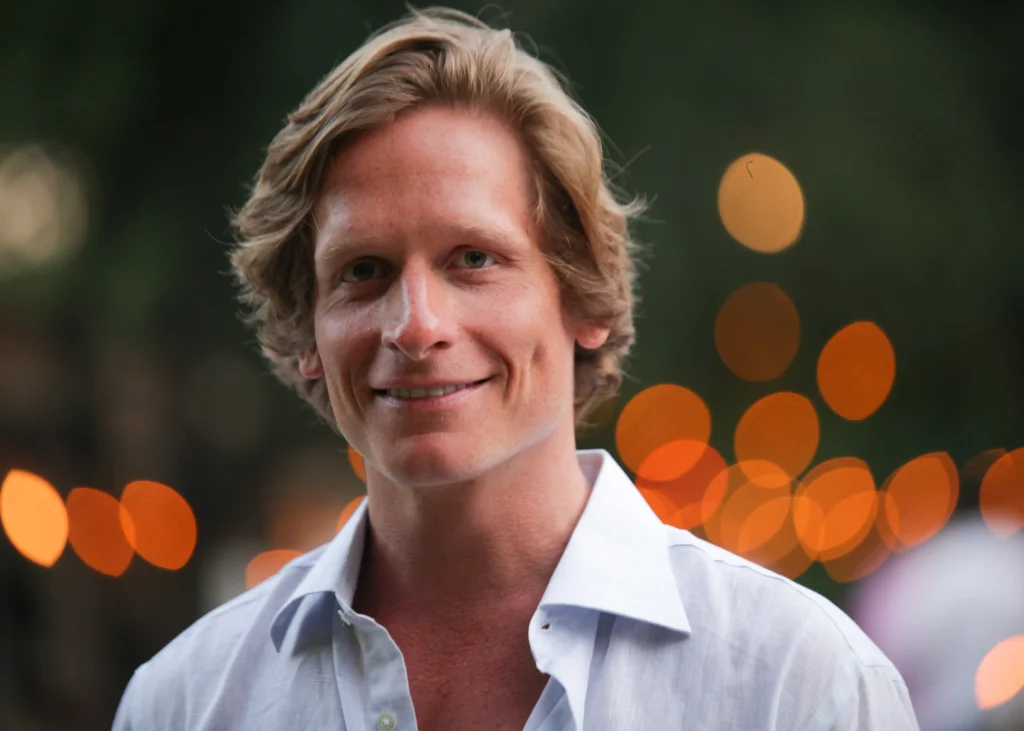 Benjamin Luke Weil in a button up shirt with city lights behind him