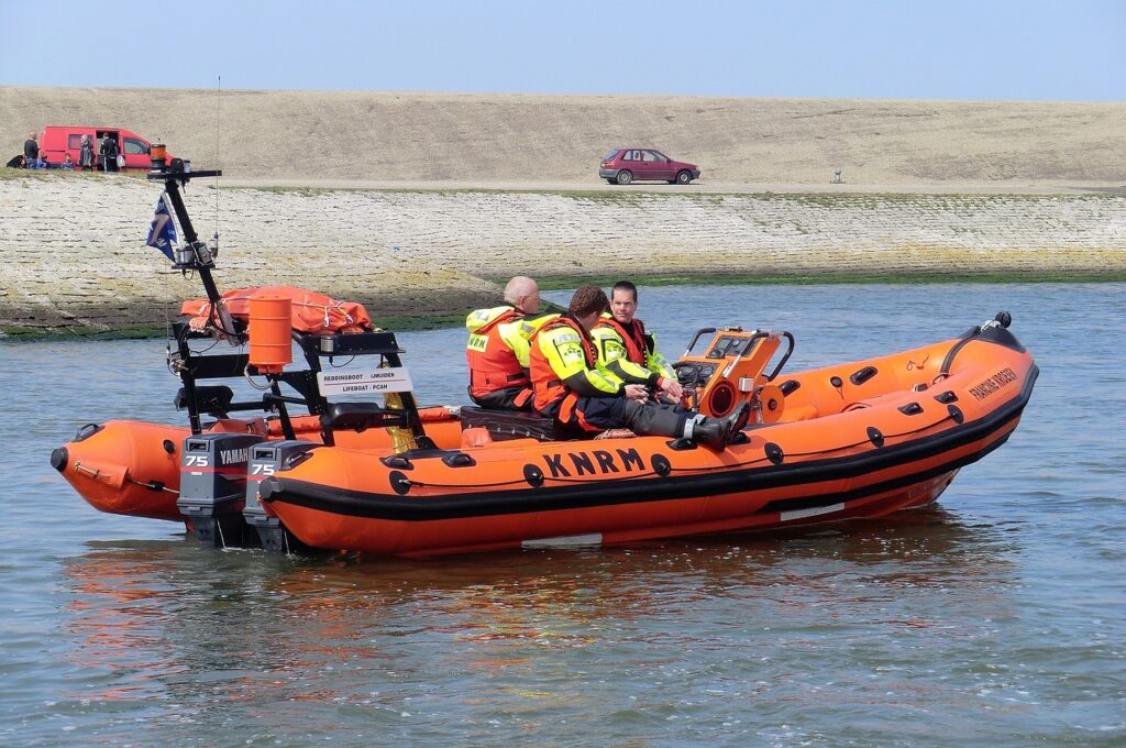 An orange lifeboat on a the water with officials on it