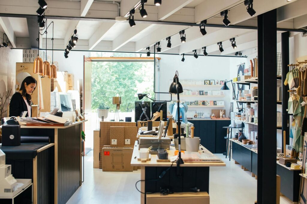 Young ethnic female employee standing at counter in creative gift shop