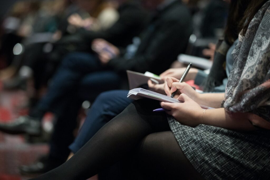 A group of news reporters sitting in a row taking notes