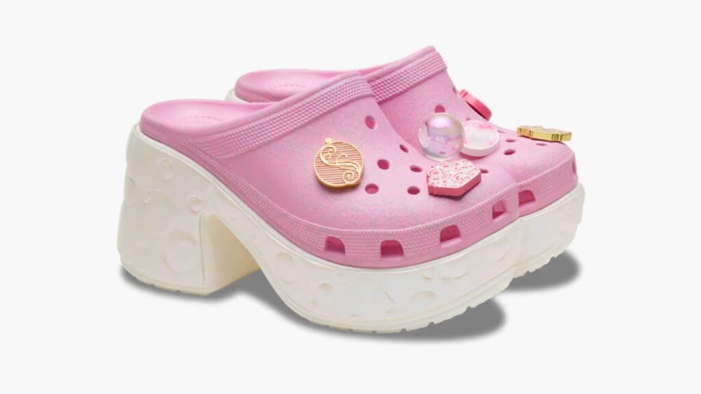 Pink heeled crocs with bubble designs on the soles with "Wicked" themed charms