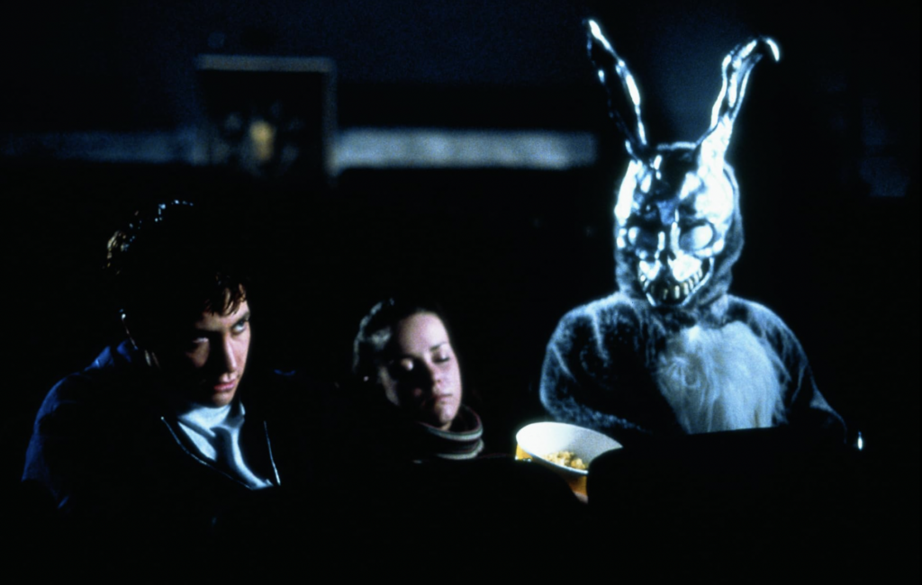 scene from Donnie Dark where Donnie, his girlfriend, and the creepy rabbit hallucination he struggles with are in a movie theater