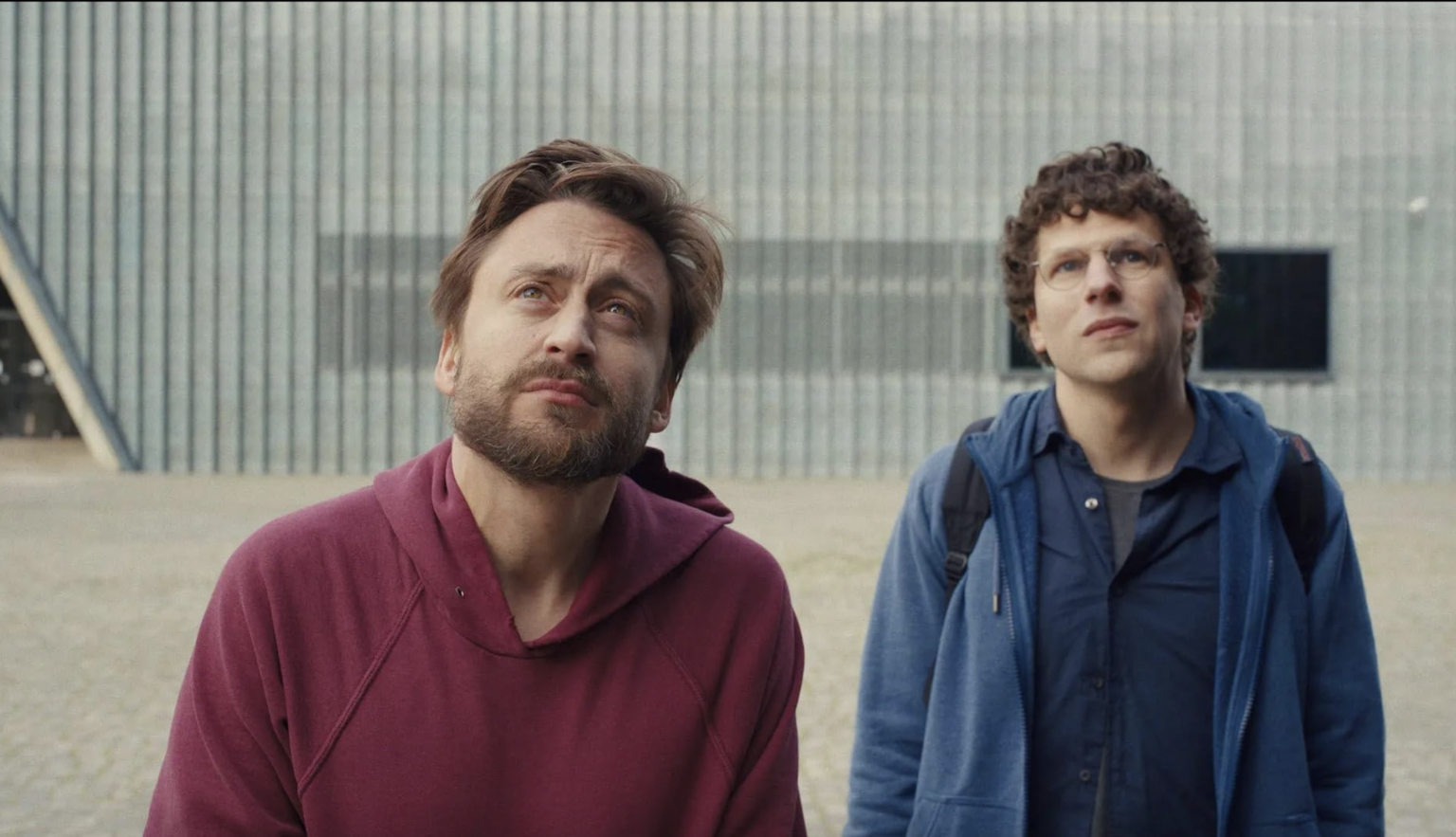 Kieran Culkin, Jesse Eisenberg both look up in a shot from A Real Pain