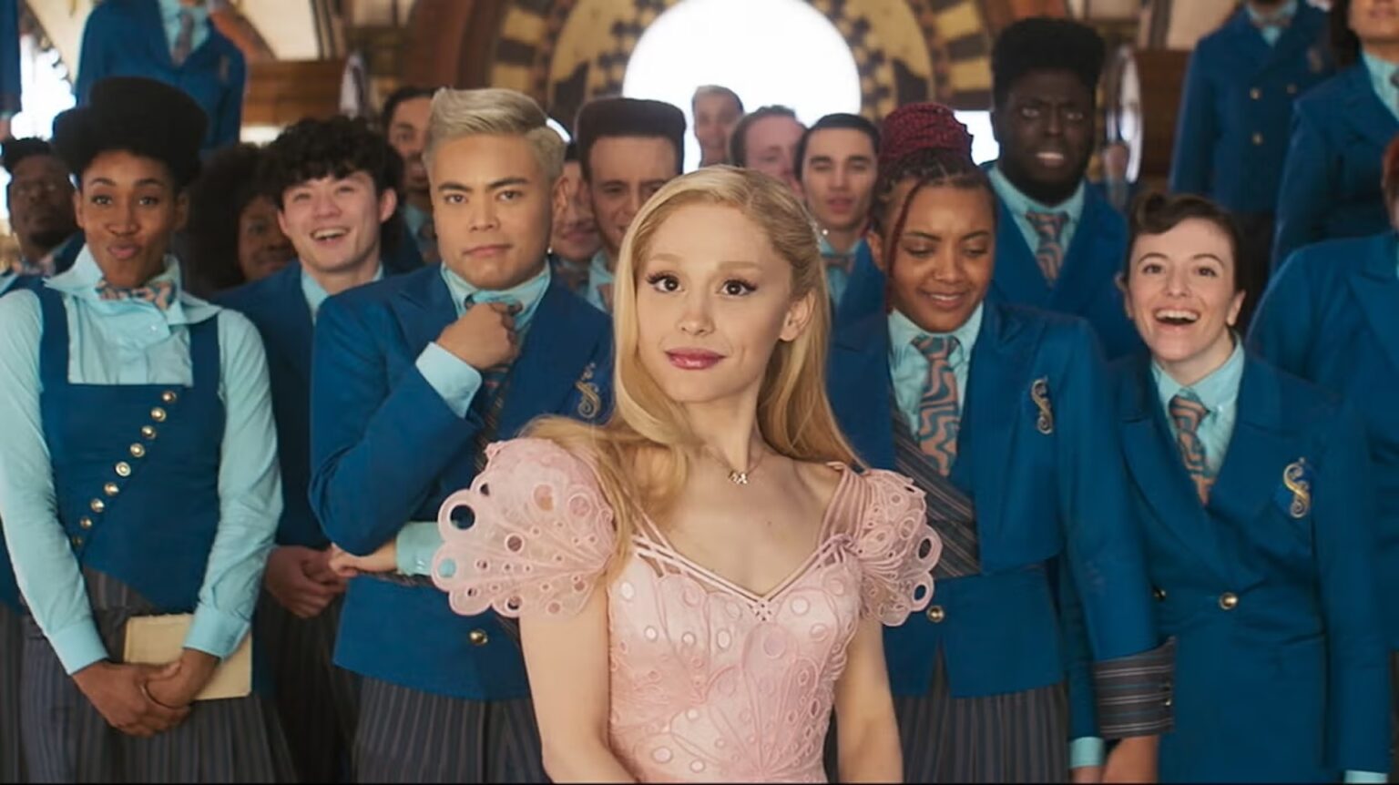 Galinda (Ariana Grande) and other Shiz students in their blue uniforms in a library in 'Wicked;' This ‘Wicked’ Dance Is Already a TikTok Sensation